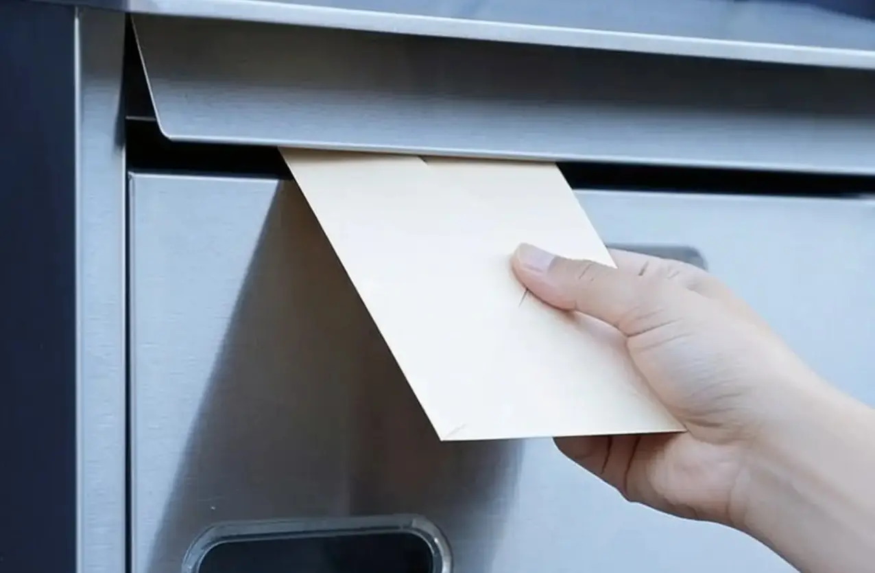 Post wird in einen Briefkasten eingeworfen – Postservice bei CoWorking SchloHo