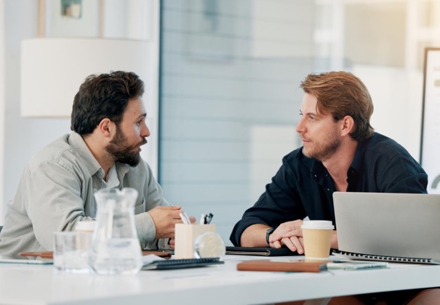 Zwei Geschäftspartner im Gespräch am Besprechungstisch mit Laptop und Kaffee im Meetingraum von CoWorking SchloHo